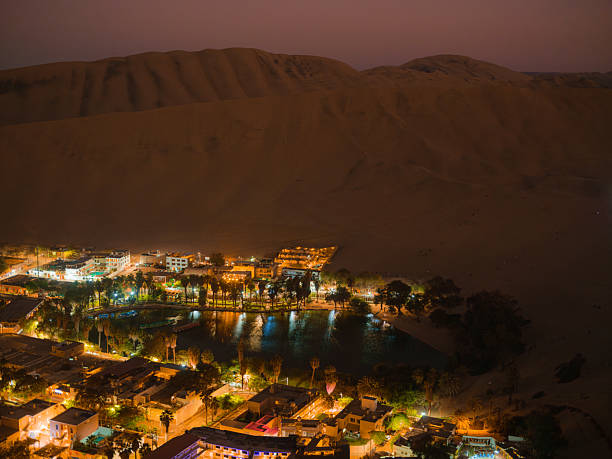 Pueblo iluminado en el oasis de Huacachina en Perú por la noche
